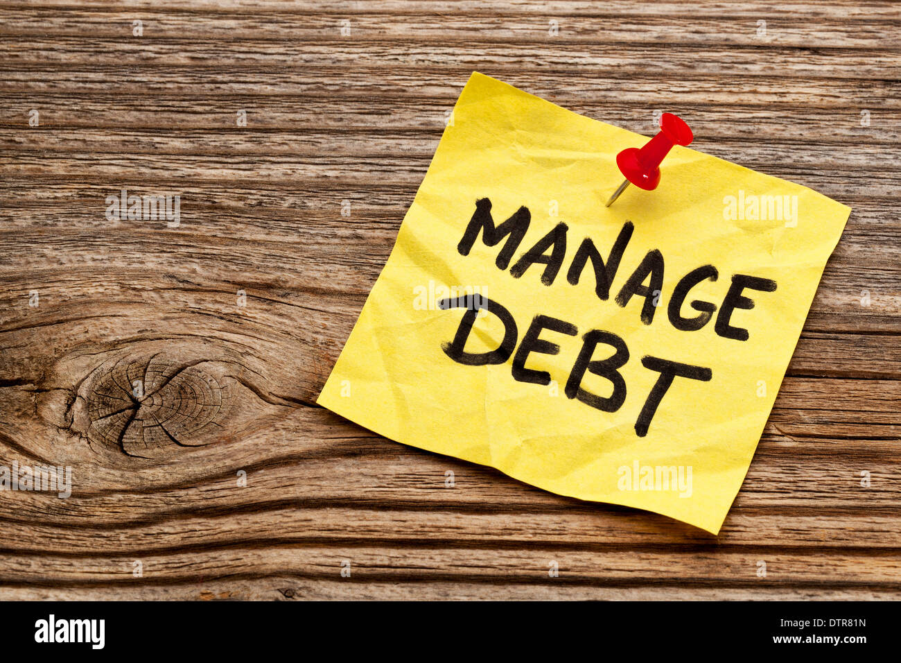 Schulden - gelbe Notiz gegen gemaserte Holz Brett zu verwalten Stockfoto