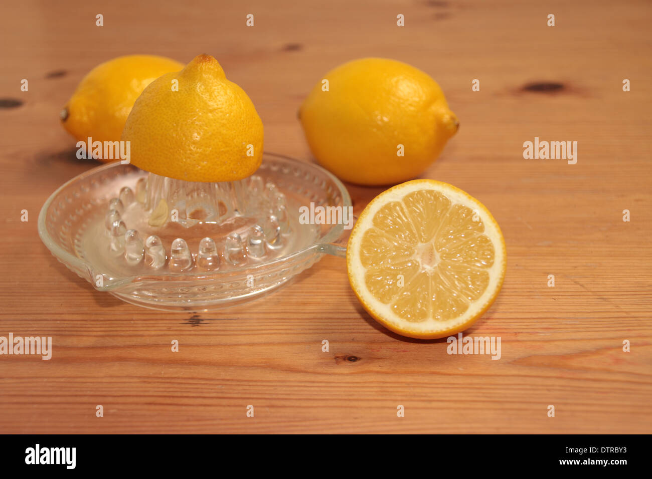 halben Zitrone gequetscht auf ein Glas Saftpresse/Entsafter mit zwei und eine halbe Zitronen im Hintergrund auf Kiefer (4 Serie von 4) Stockfoto