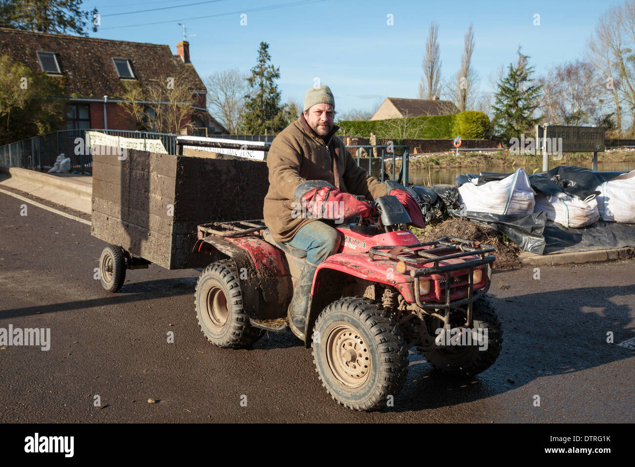 Kneipe Vermieter Jim Winkworth verwendet ein Quad mit Anhänger liefern Lieferungen und rette Tiere von den schweren Überschwemmungen in Burrowbridge am 22. Februar 2014. Als Vermieter von König Alfred Inn hat er auch Hochwasser gefährdeten aber hilft seit seinem Einheimischen mit Besorgungen während der Krise besuchen Dörfer von Moor- und Fordgate an den Ufern des Flusses Parrett Reisen. Stockfoto