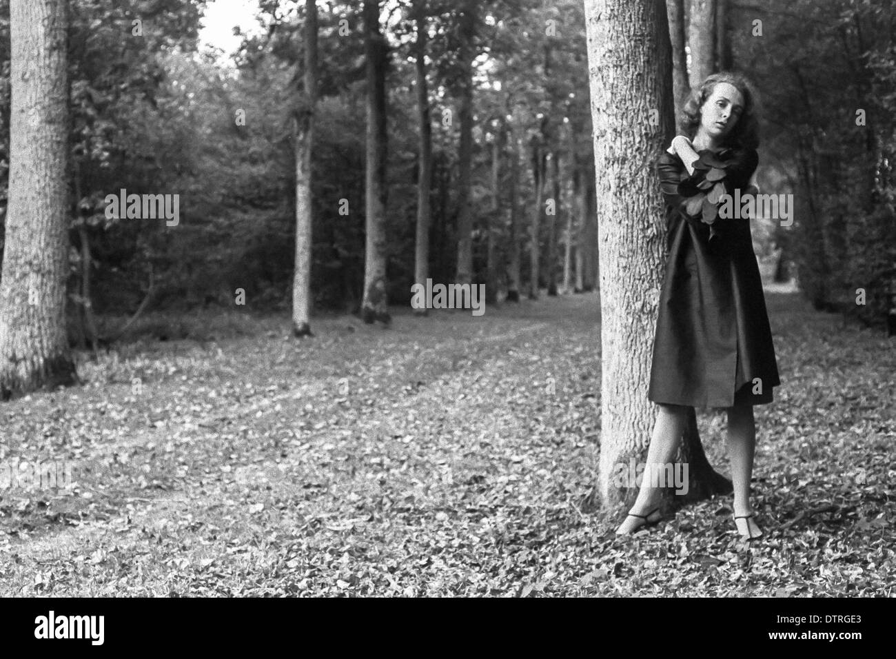 60er Jahre Mode Modell mit schwarzen Mantel posiert im Wald Stockfoto