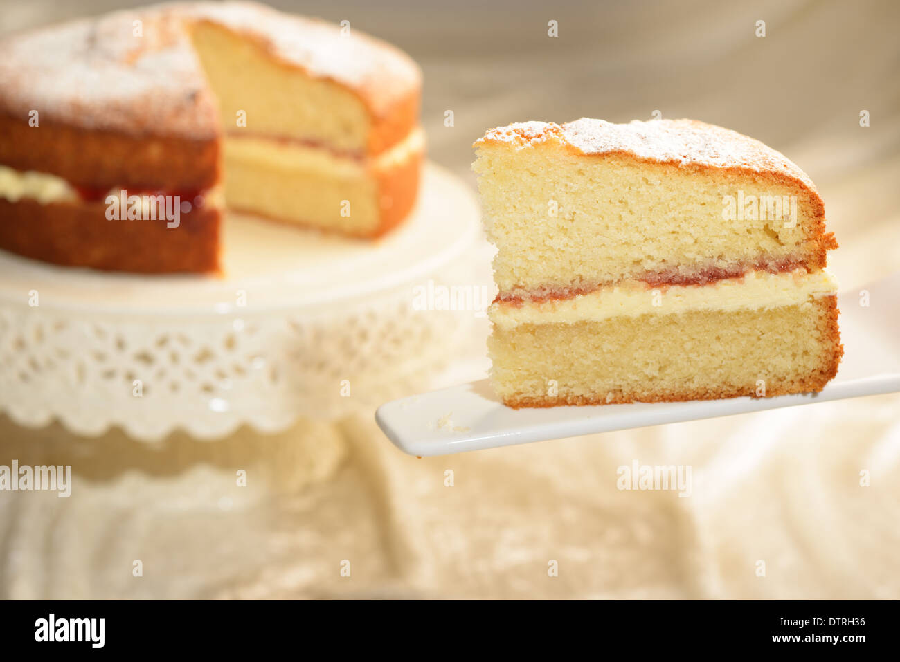 Ein Stück von Victoria Biskuit mit geschnittenen Kuchen im Hintergrund Stockfoto