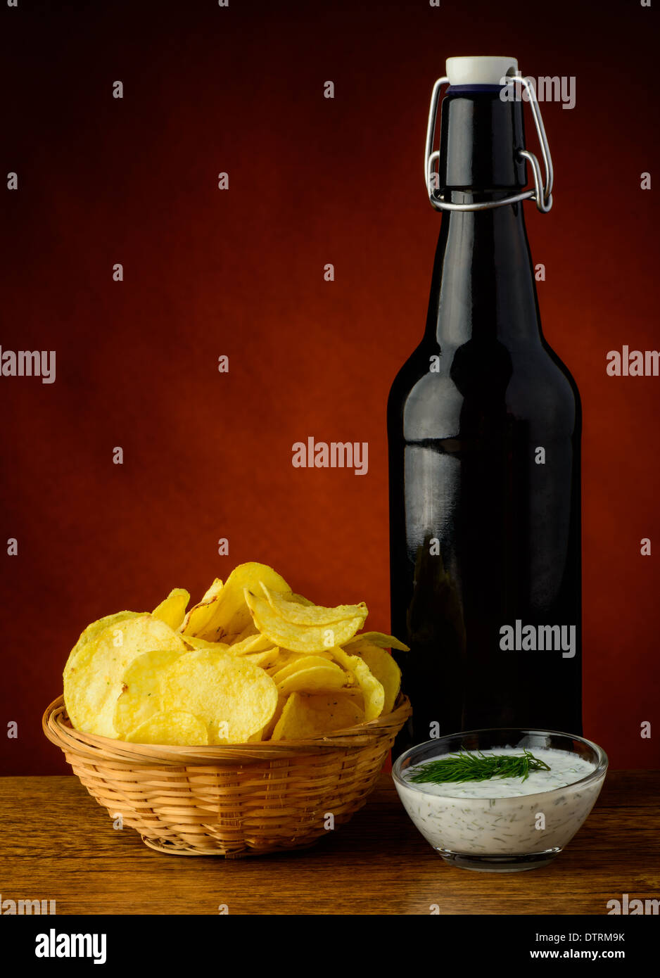 Stillleben mit Kartoffel-Chips, Dill-Dip und Bier Flasche Stockfoto