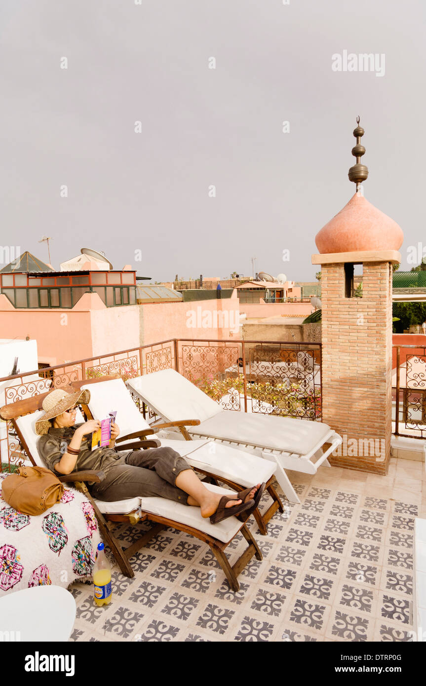 Eine Frau liest ein Buch auf einer Dachterrasse des Hotel du Tresor, einem Riad in Marrakesch, Marokko. Stockfoto