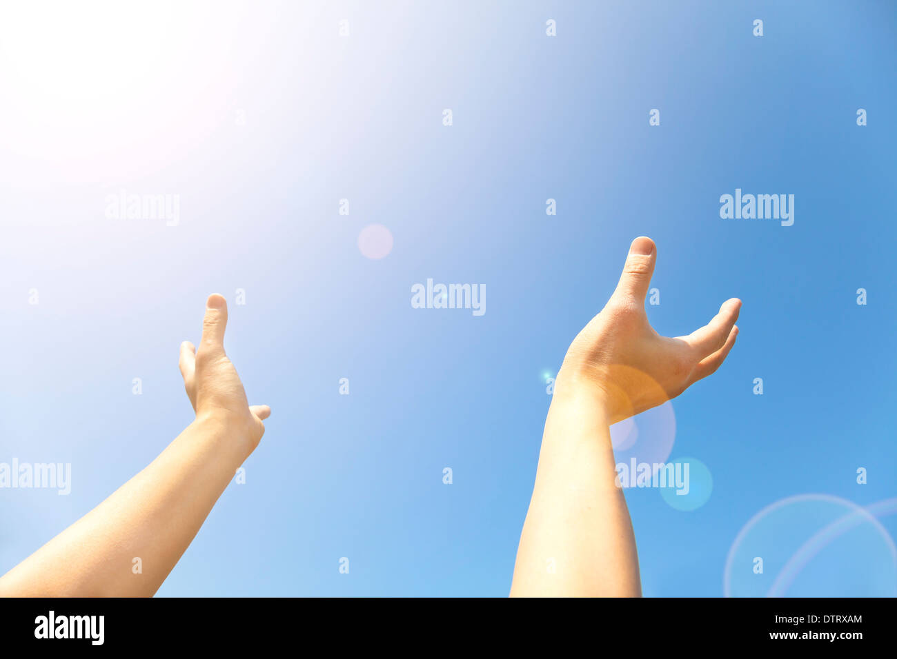 Zwei Hände mit den geöffneten Handflächen dauern nach oben in den blauen Himmel Stockfoto