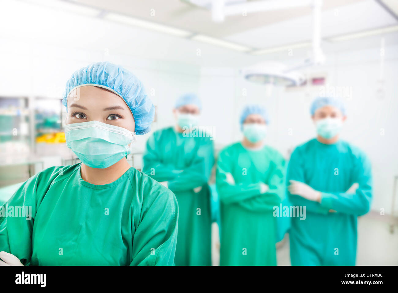 Lächelnd Chirurg posiert mit ästhetischen Medizin-Teams in einem OP-Saal Stockfoto