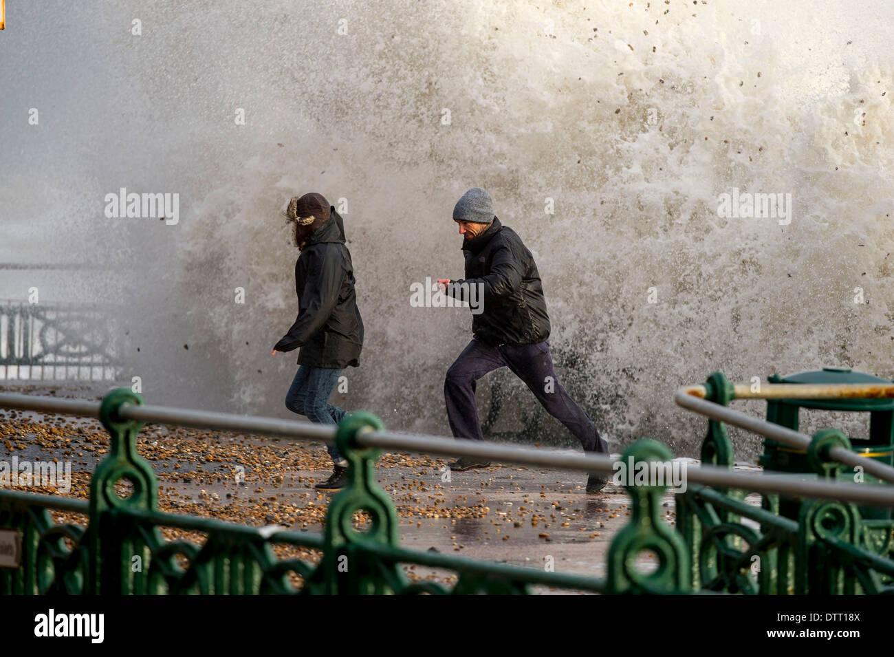 Ein Mann läuft von riesigen Wellen während der Gezeiten Überspannungen auf britischen Küsten bei extremem Wetter. Szene in Brighton, Sussex, Großbritannien Stockfoto