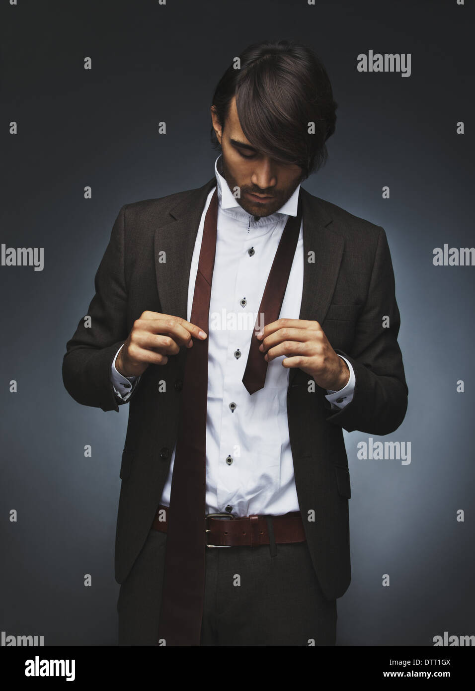 Bild der junge Geschäftsmann im Anzug, die Krawatte zu tragen. Schöne männliche Fotomodell anziehen auf schwarzem Hintergrund Stockfoto