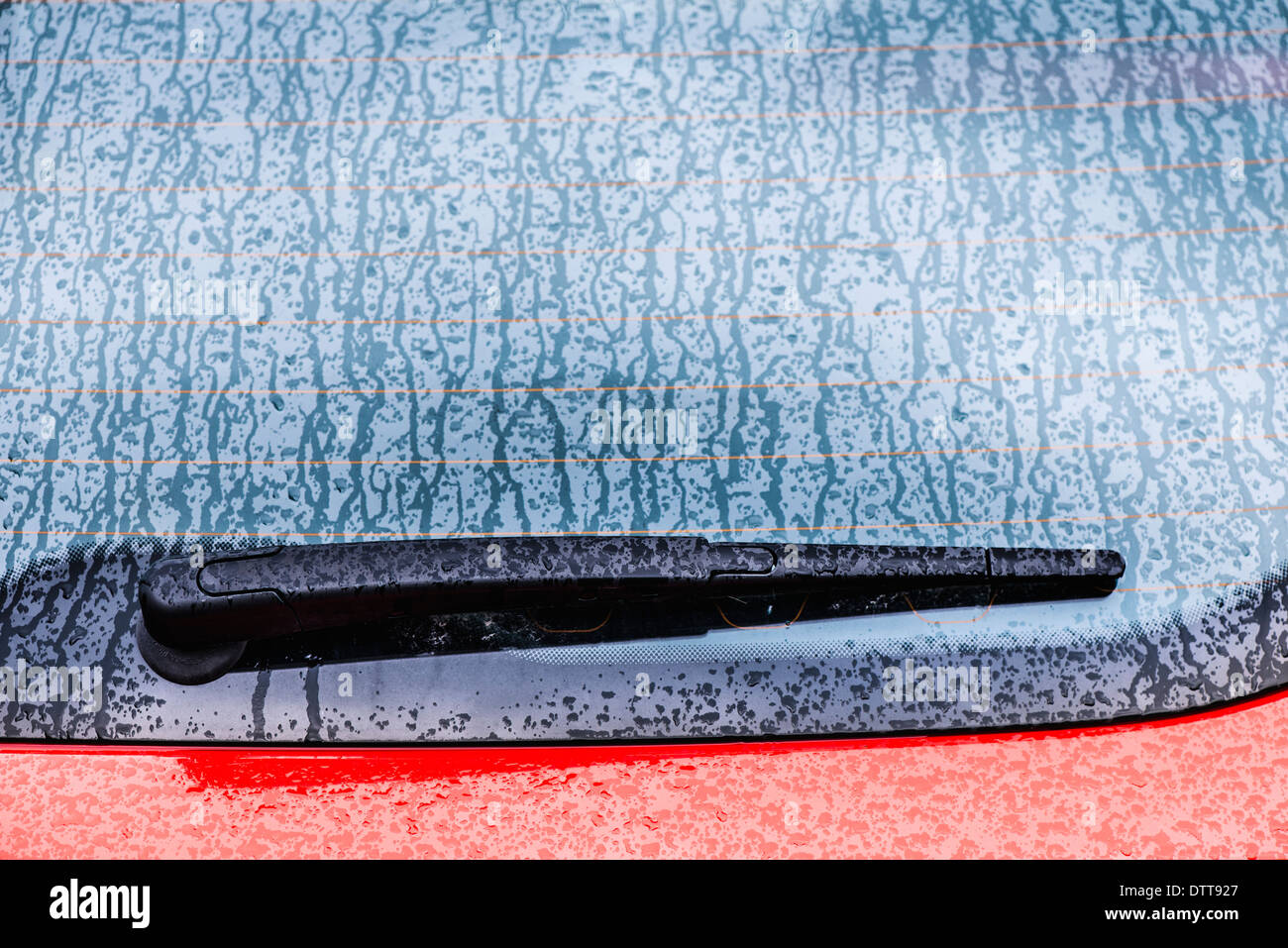 Detail der nassen roten Auto. Scheibenwischer und einem verregneten Fenster. Stockfoto