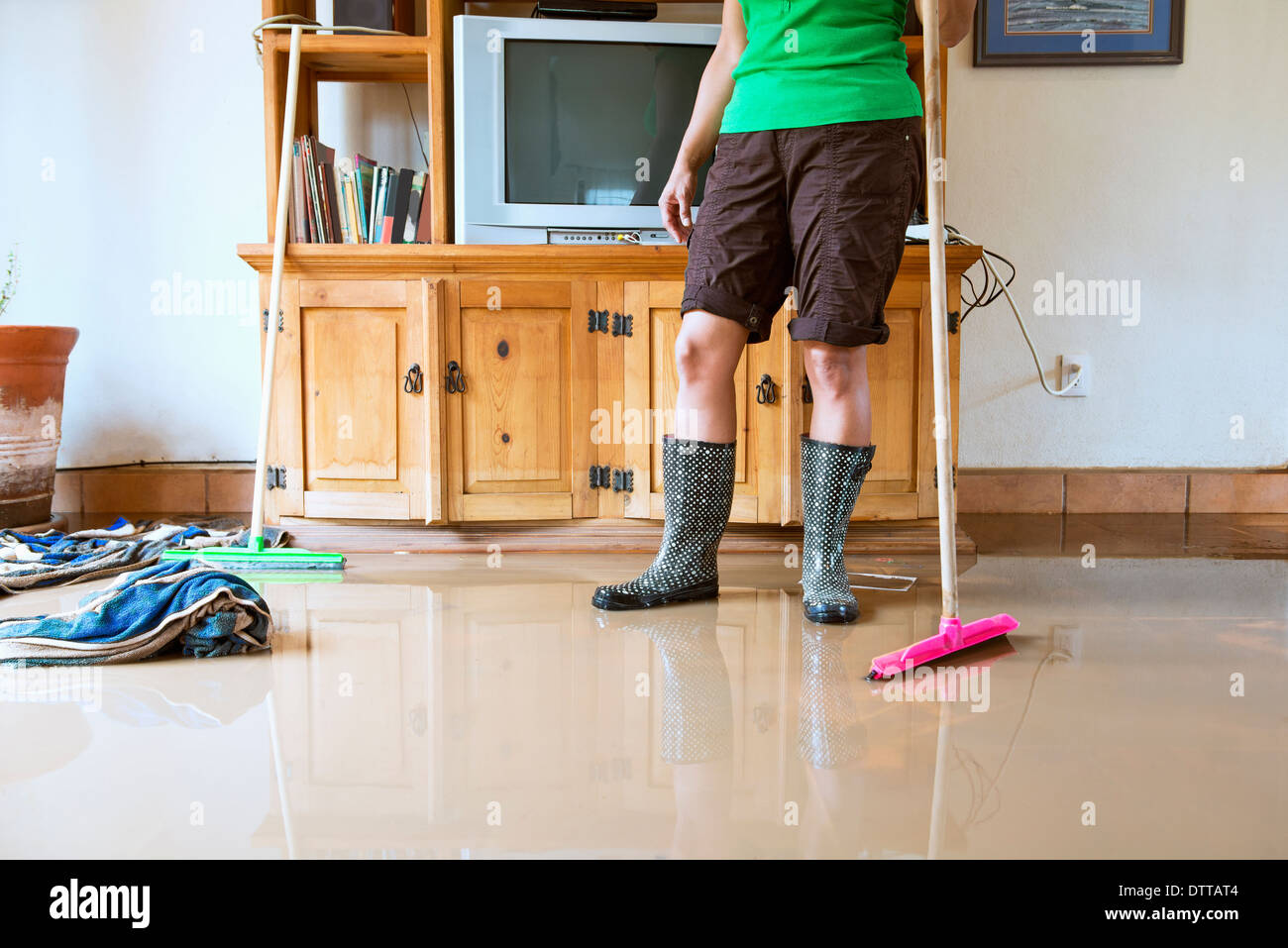 Hispanic Frau Wasser aus überfluteten Haus kehren Stockfoto