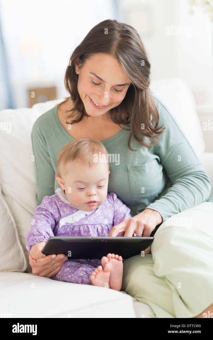 Kaukasische Mutter lesen Baby mit Down-Syndrom Stockfoto