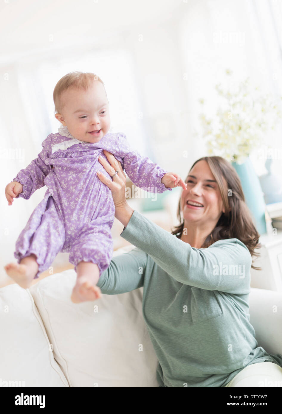 Kaukasische Mutter spielen mit Baby mit Down-Syndrom Stockfoto