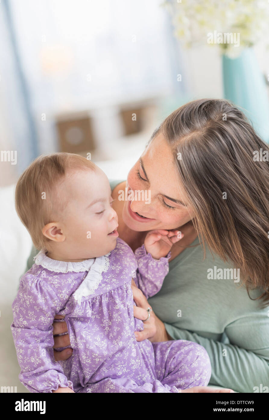 Kaukasische Mutter spielen mit Baby mit Down-Syndrom Stockfoto