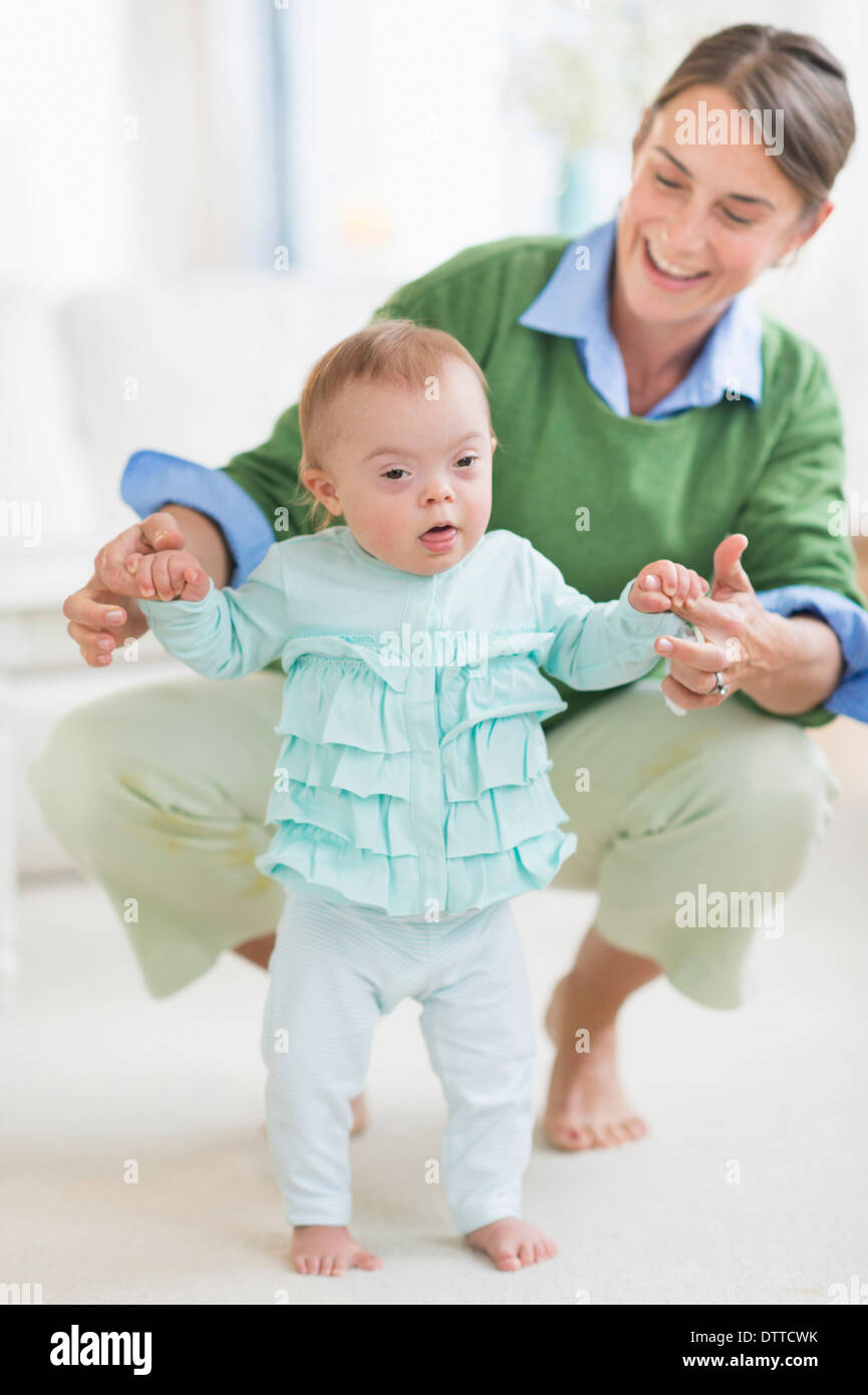 Kaukasische Mutter helfen Baby mit Down-Syndrom zu Fuß Stockfoto