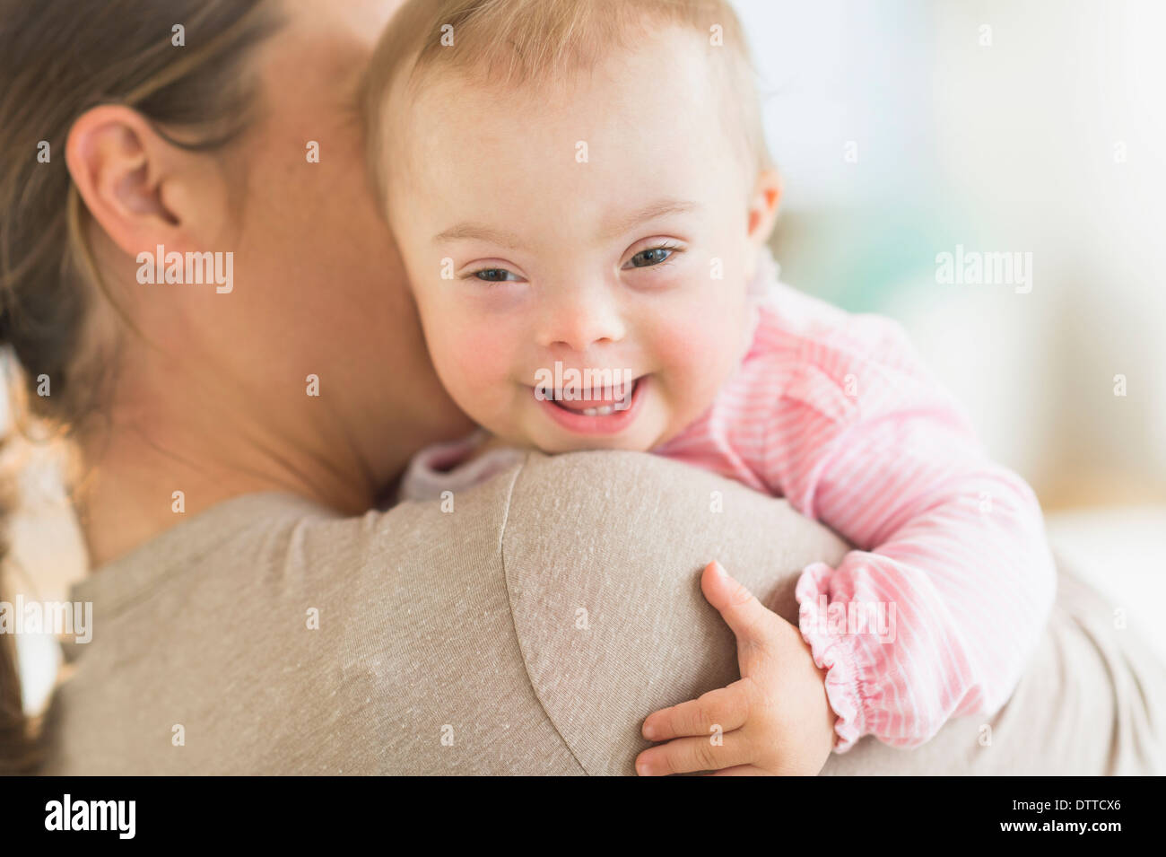 Kaukasische Mutter hält Babymädchen mit Down-Syndrom Stockfoto