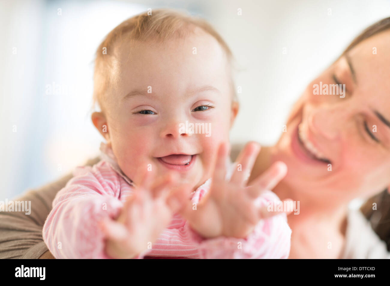 Kaukasische Mutter spielen mit Babymädchen mit Down-Syndrom Stockfoto