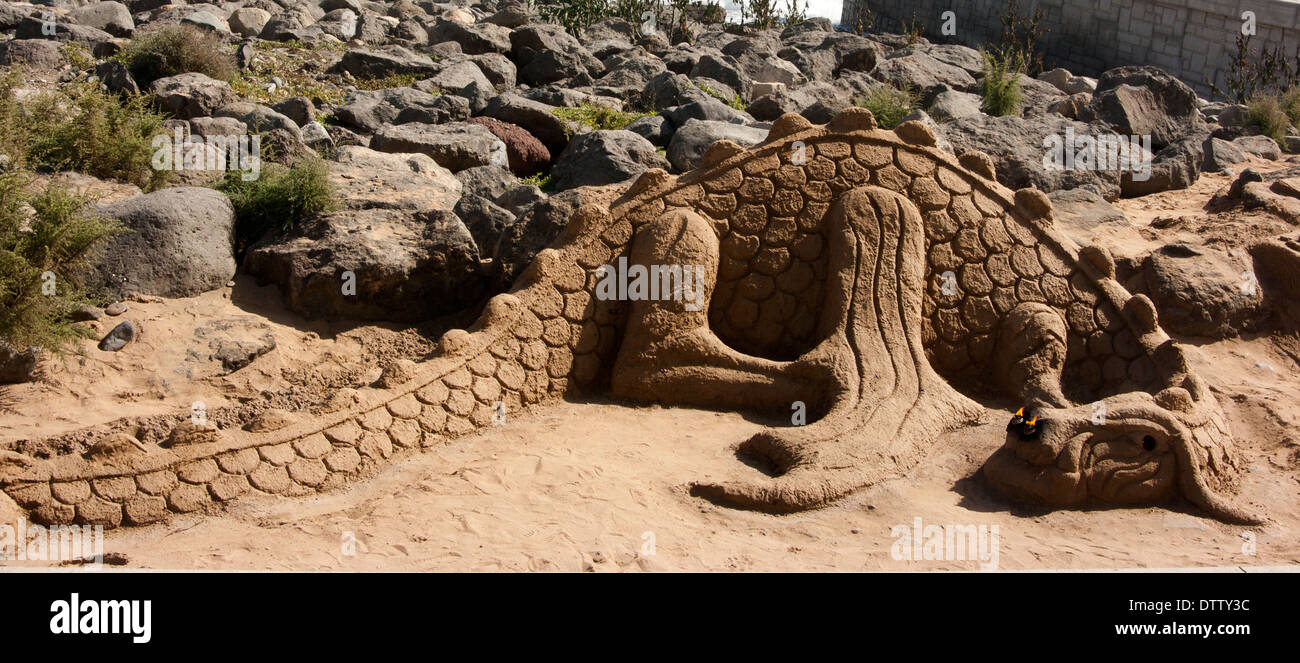 Sandskulptur eines Drachen mit flammenden Nasenlöcher am Strand von Maspalomas, Gran Canaria, Kanarische Inseln Stockfoto