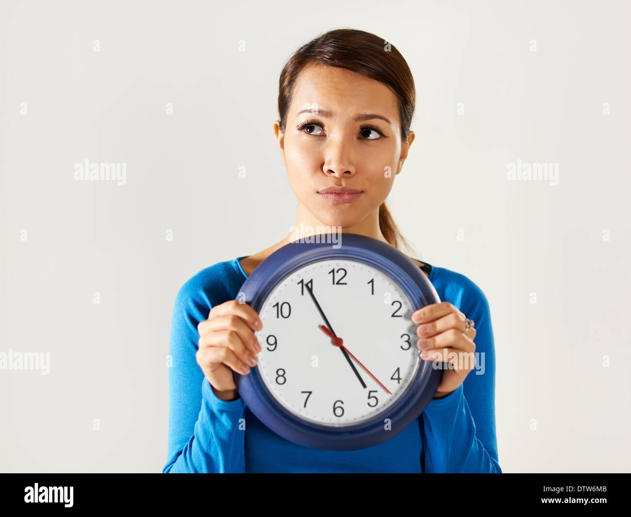 Porträt des asiatischen Geschäftsfrau hält große blaue Armbanduhr und wegschauen mit Sorge Ausdruck. Textfreiraum Stockfoto