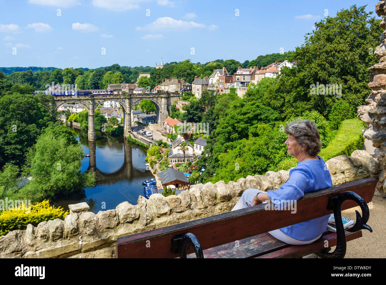 Ältere Frau sitzen auf Bank in der Nähe der Burg mit Blick auf Fluss Nidd und Viadukt, Knaresborough, North Yorkshire, England, UK Stockfoto