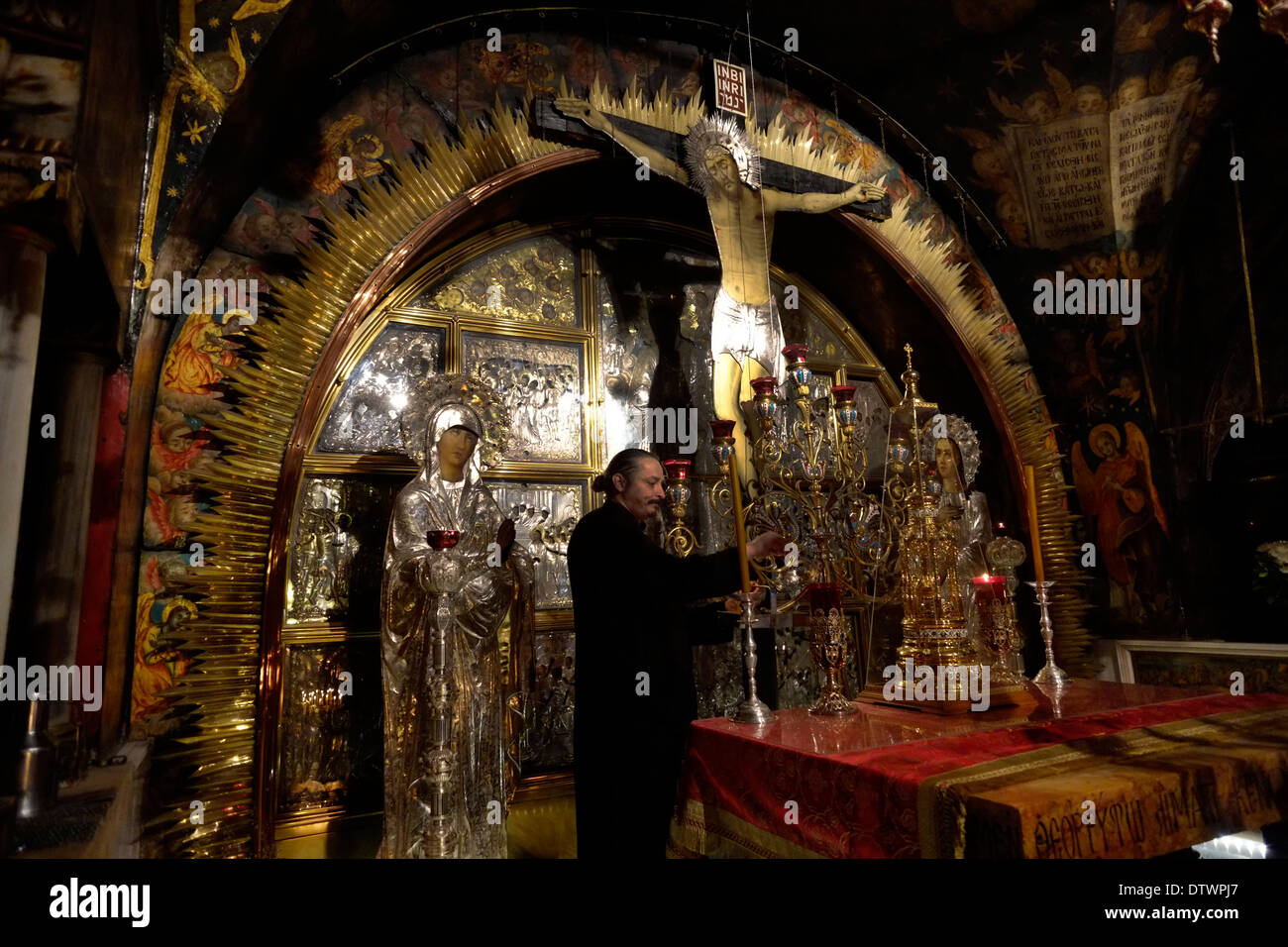 Ein griechischorthodoxer Kleriker zündet Kerzen am Altar der Kreuzigung im Golgatha an, der