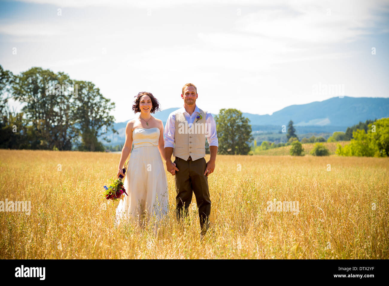 Braut und Bräutigam am Tag ihrer Hochzeit zusammen in einem Feld stehen. Stockfoto
