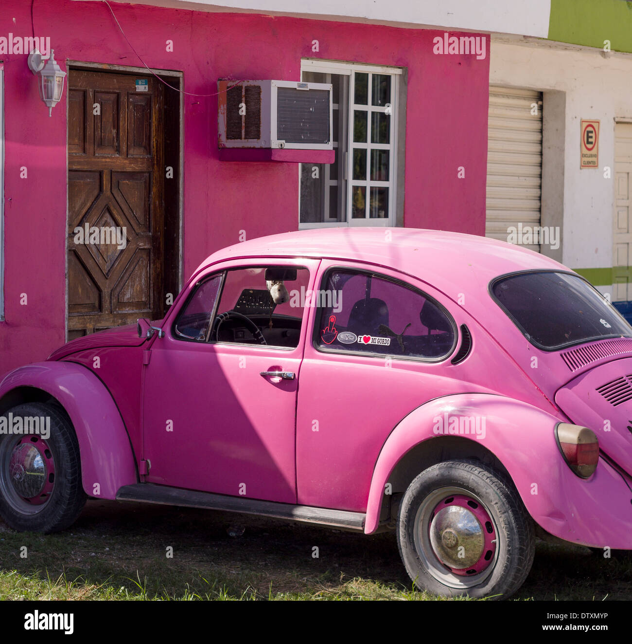 Rosa VW und passende Haus. Ein heller rosa VW Käfer vor einem rosa Haus geparkt. Tulum, Quintana Roo, Mexiko Stockfoto