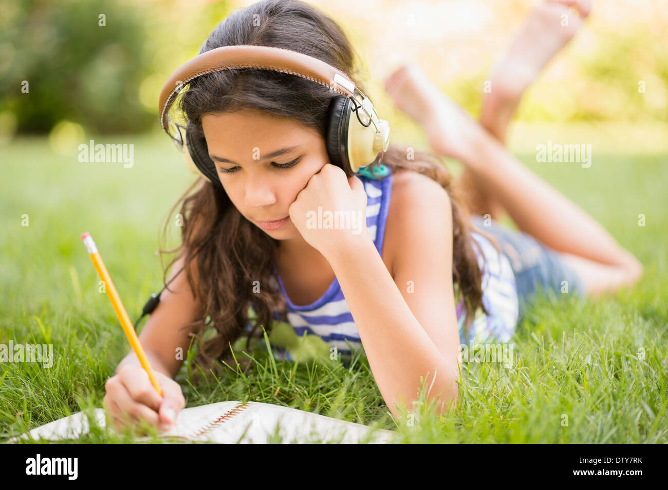 Gemischte Rassen Mädchen Kopfhörer anhören und Zeichnung in Rasen Stockfoto