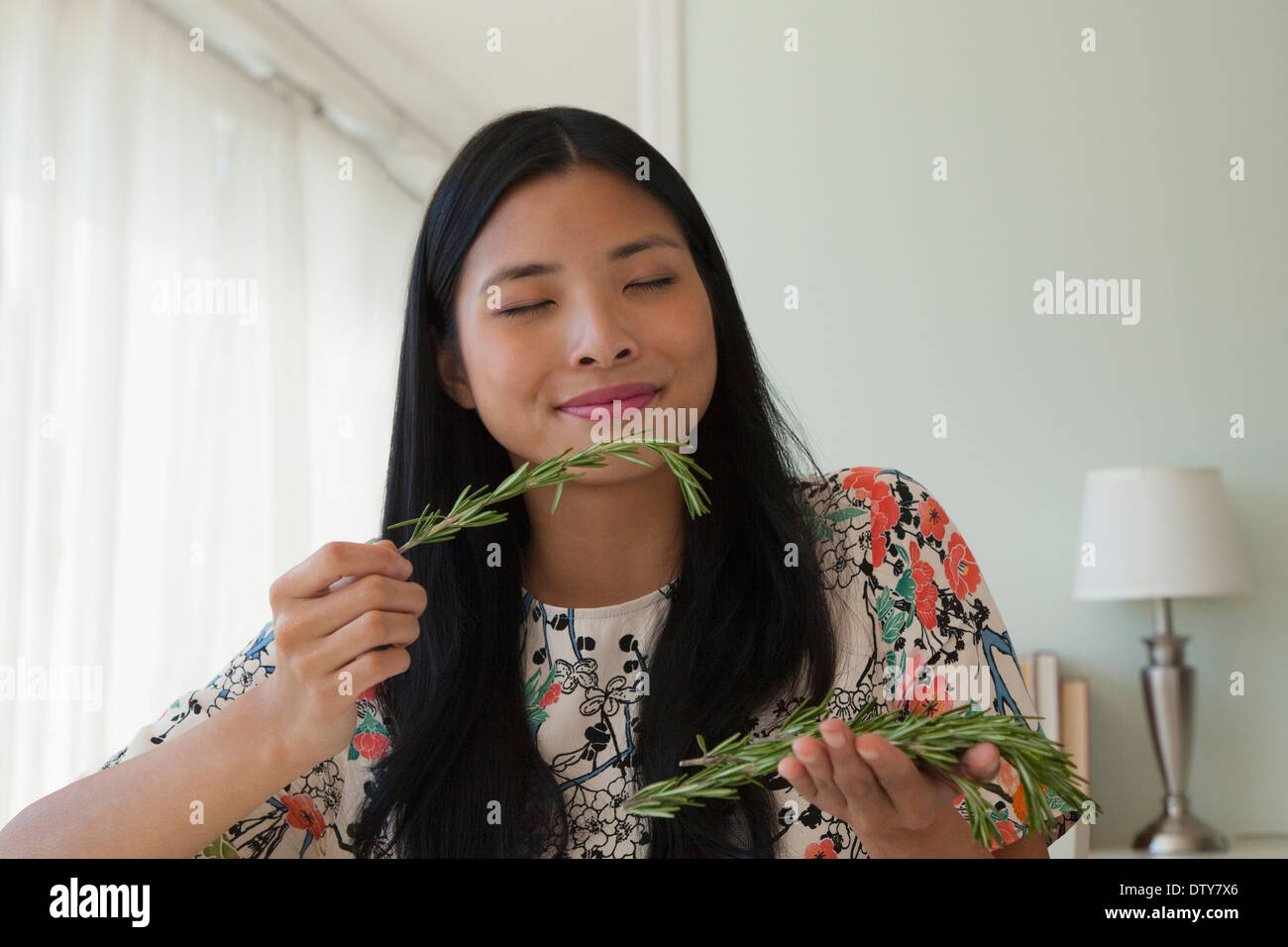 Chinesische Frau riecht frischen Rosmarin Stockfoto