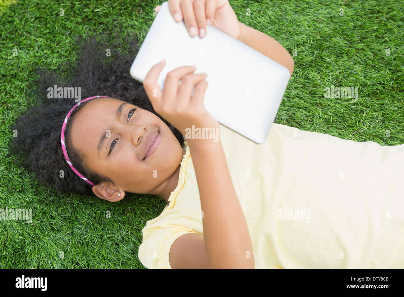 Gemischte Rassen Mädchen mit digital-Tablette in Rasen Stockfoto