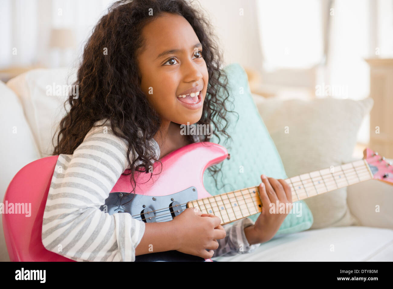 Gemischte Rassen Mädchen spielt e-Gitarre auf sofa Stockfoto