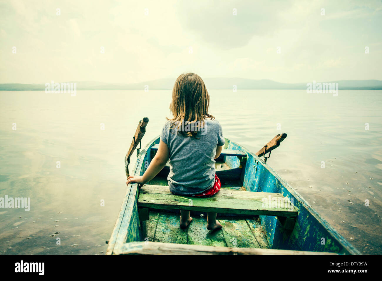 Kaukasische Mädchen sitzen im Boot auf noch See Stockfoto