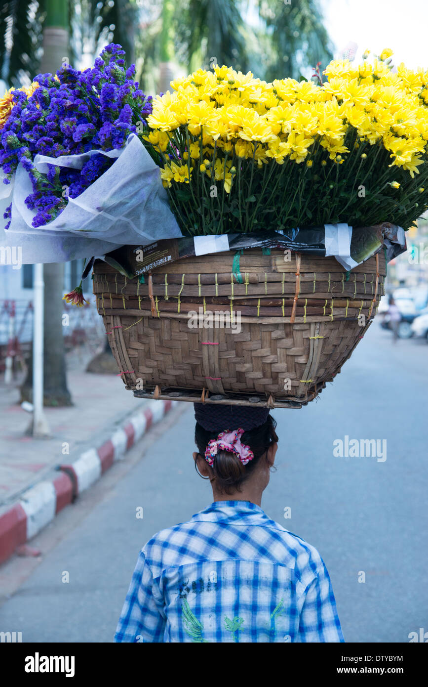 Frau, die große Blumenkorb auf dem Kopf trägt. Yangon. Myanmar (Burma). Stockfoto
