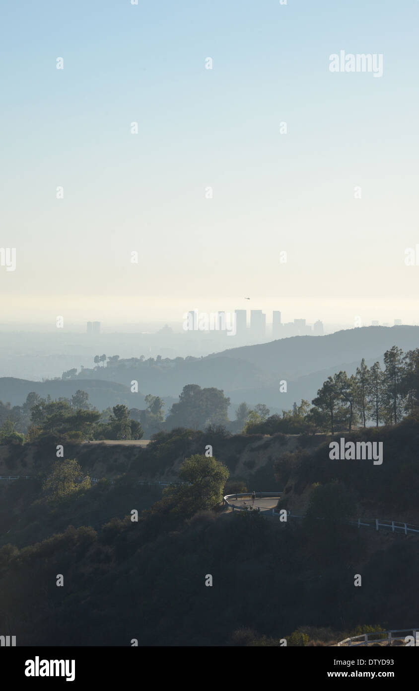 Los Angeles im fernen Nebel über einem sich schlängelnden Mulholland Drive in den Hollywood Hills Stockfoto