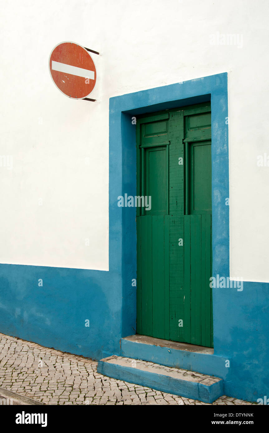 Alte grüne Tür inmitten einer blau-weißen Wand mit einem roten kein Eintrag Straßenschild, Portugal Stockfoto