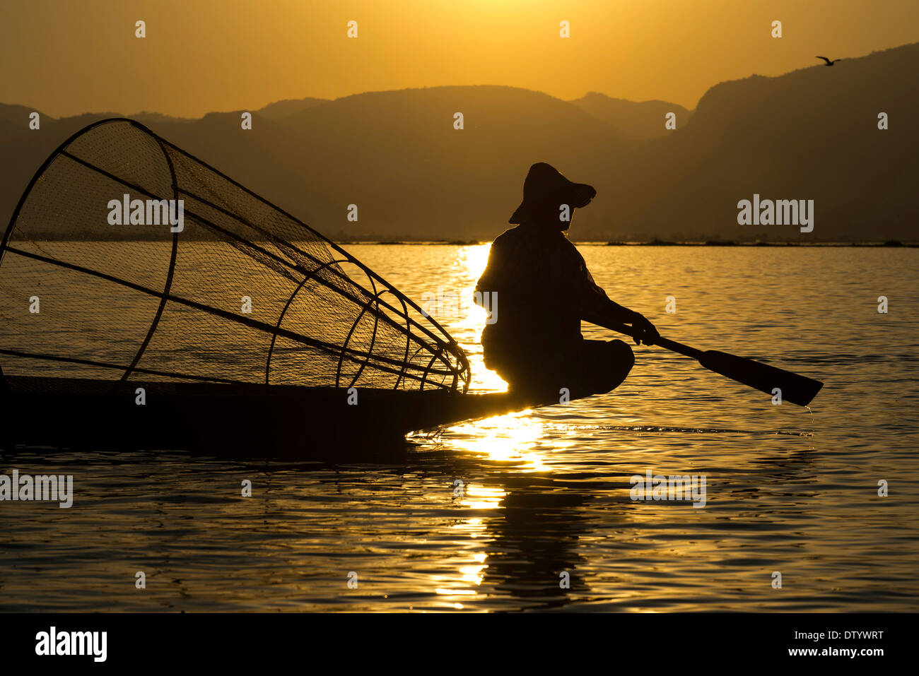 Fischer im Abendlicht, mit einem traditionellen Korb, sitzen auf dem Kanu, Sonnenuntergang am Inle-See, Shan State in Myanmar Stockfoto