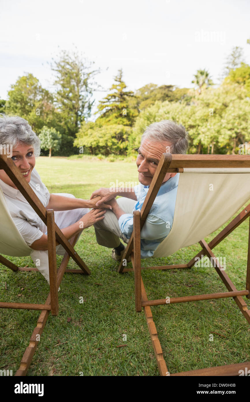 Älteres Paar auf Liegestühlen liegend lächelnd Stockfoto