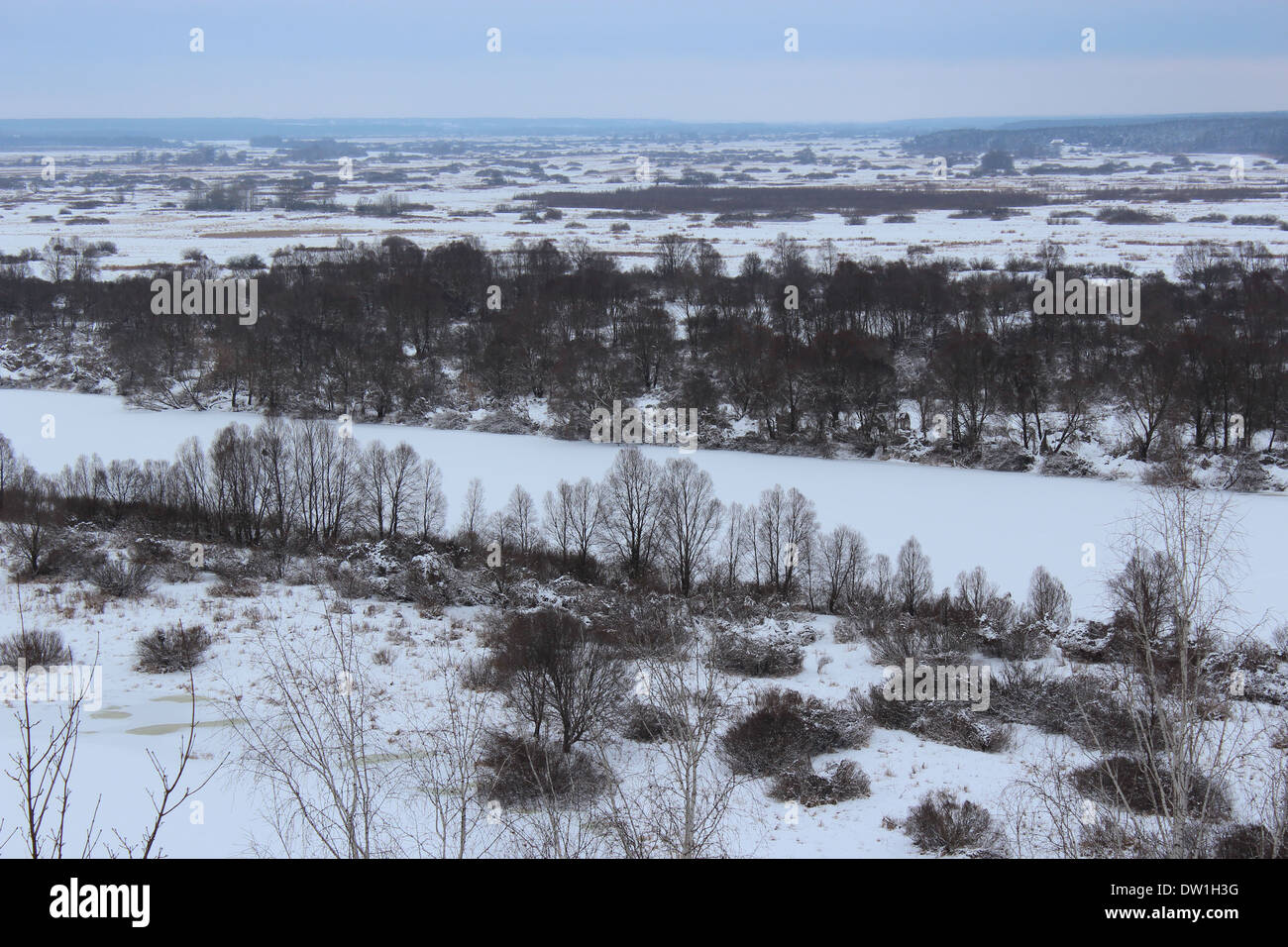 Winter-Feld, gefrorene weiße Fluss und Wald auf dem Hintergrund Stockfoto