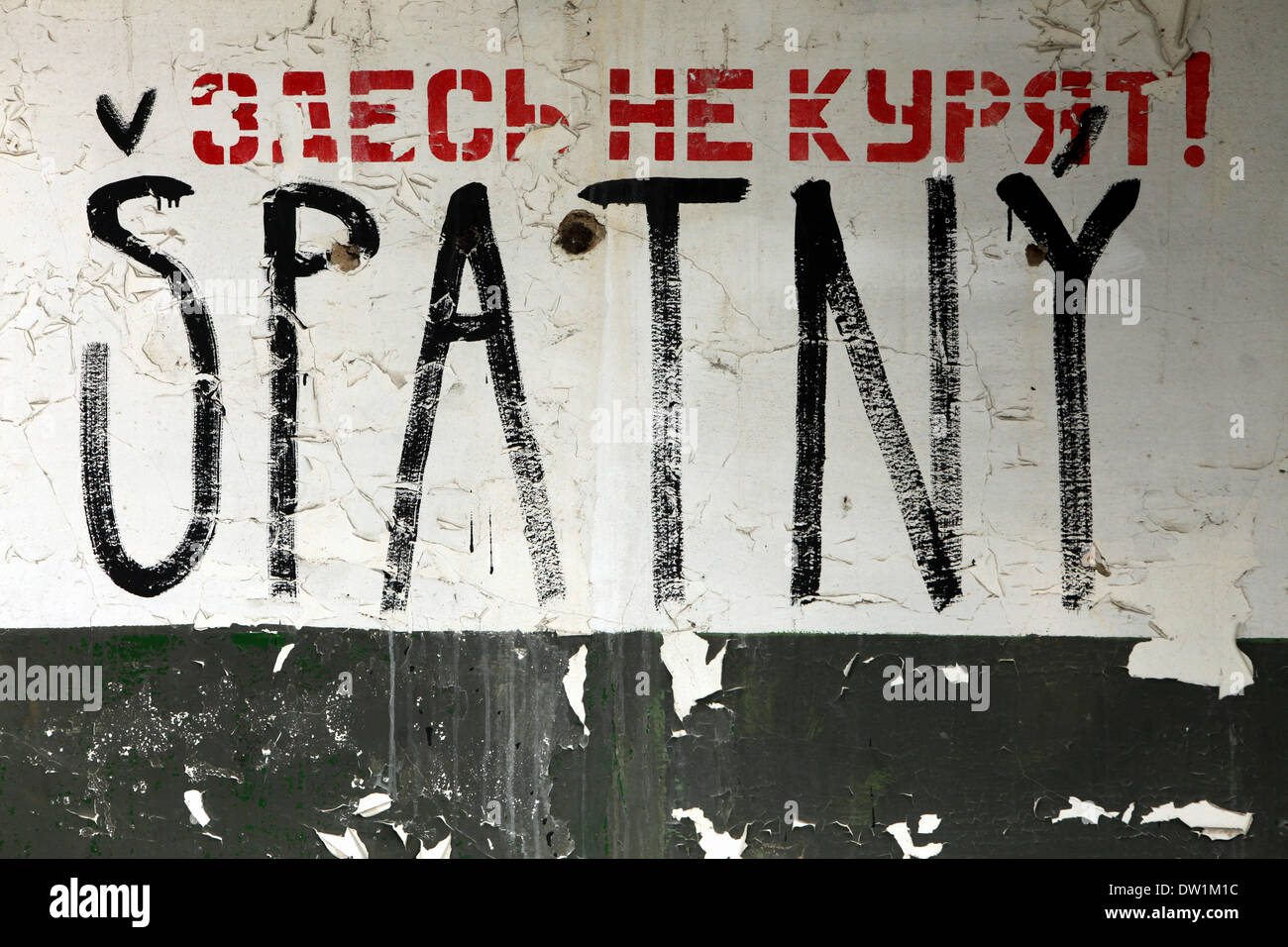 Milovice, Tschechische Republik. 25. Februar 2014. Ein Sowjet-Ära Verbot unterzeichnen "Rauchen verboten!" auf Russisch und Graffiti "Spatny" in Tschechien ("Falsch" oder "Schlecht") an der Wand eines verlassenen Gebäudes im Bereich der sowjetischen Militärbasis in Milovice, liegt etwa 40 km von Prag, Tschechien. Ruinen der ehemaligen sowjetischen Militärbasis in Milovice sollen in kommenden Monaten um Platz für neue Gebäude abgerissen werden. Die Basis hat seit mehr als zwanzig Jahren aufgegeben worden, da die sowjetischen linke Tschechoslowakei im Jahr 1991 Truppen. Jetzt überlebt die Basis für die letzten Tage. Stockfoto