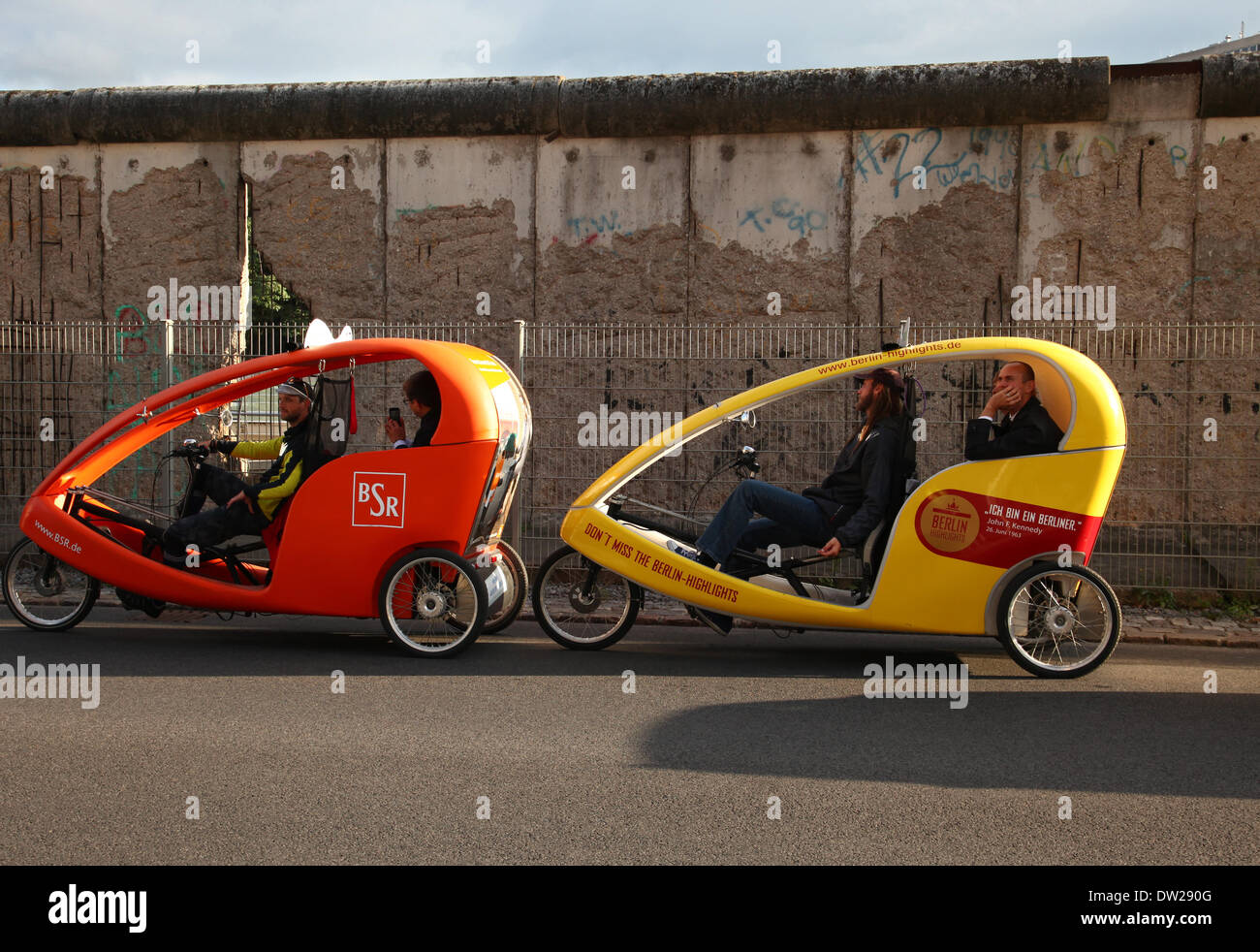 Tourist in Velo taxis fahren durch ein Stück der Berliner Mauer in Berlin, 19. September 2013. Jedes Jahr kommen immer mehr Touristen in die deutsche Hauptstadt. Das Foto ist Teil einer Serie über den Tourismus in Berlin. Foto. Wolfram Steinberg dpa Stockfoto