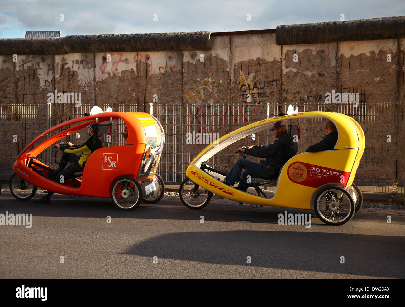 Tourist in Velo taxis fahren durch ein Stück der Berliner Mauer in Berlin, 19. September 2013. Jedes Jahr kommen immer mehr Touristen in die deutsche Hauptstadt. Das Foto ist Teil einer Serie über den Tourismus in Berlin. Foto. Wolfram Steinberg dpa Stockfoto