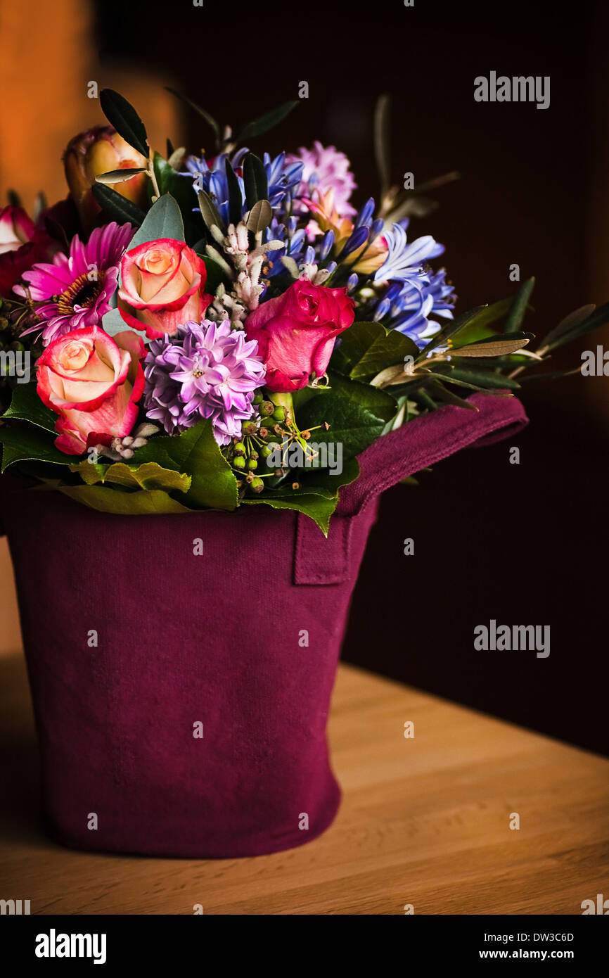 Vase gefüllt mit Frühlingsblumen und mit einem dunklen Hintergrund auf einem Tisch Stockfoto