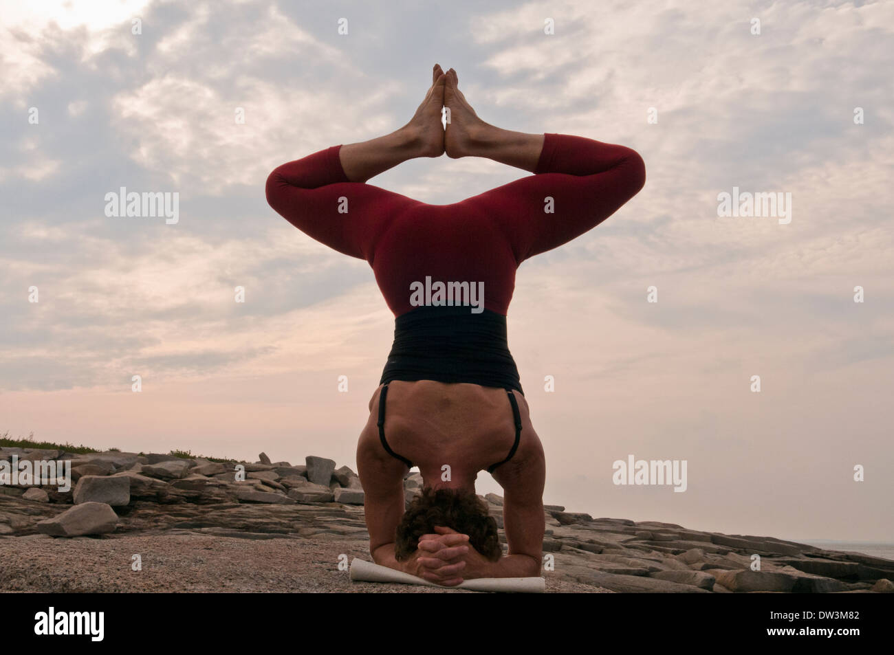 Iyengar Yoga Instructor zeigt Sirsasana von hinten Baddhakonasana (invertiert). Stockfoto