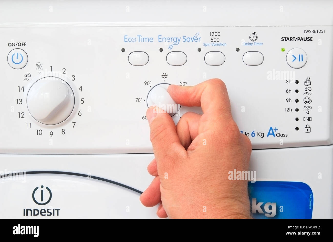 Kaukasischen Mann Hand anpassen ein Temperaturregler auf eine Indesit Waschmaschine, UK-Modell veröffentlicht Stockfoto