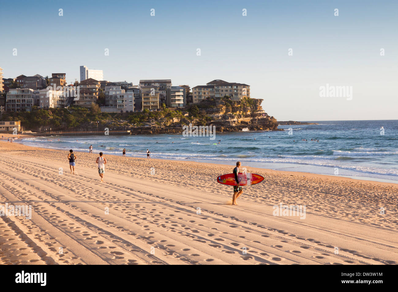 Manly North Steyne beach Surfer zu Fuß in Richtung Meer, Läufer im Hintergrund nördlichen Strände Sydney New South Wales NSW Australia Stockfoto