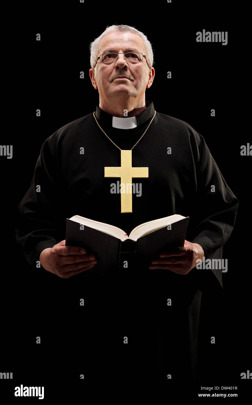 Katholische Pfarrer hält eine Bibel und beten Stockfoto