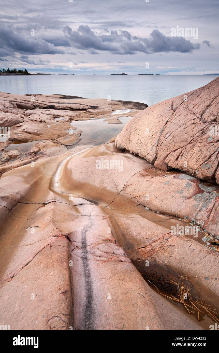 Ein Beispiel für Felsen ausgehöhlt durch Wasser und Eis mit dramatischen Sturmwolken über Georgian Bay, Ontario, Kanada. Stockfoto