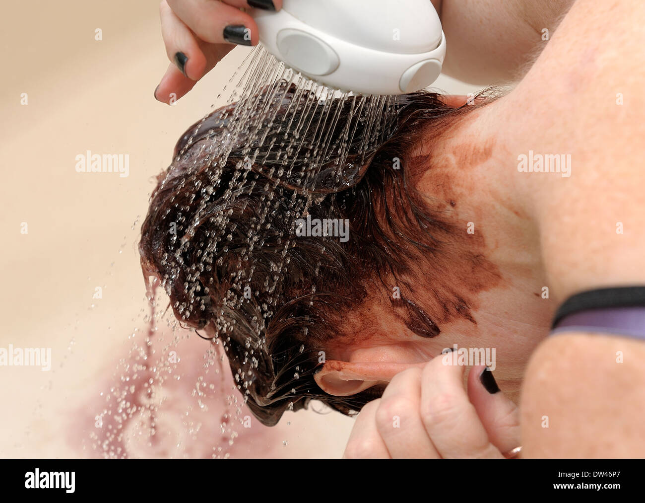 Frau, die Haare färben über eine Badewanne mit einem Duschkopf spülen Stockfoto