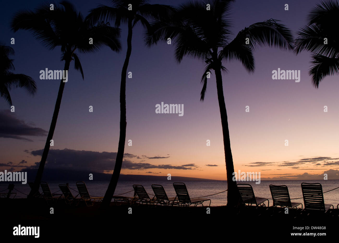 Dämmerung lila Sonnenuntergang am erholsamen Kahana Strand am Wasser mit Stühlen auf Maui Hawaii Stockfoto