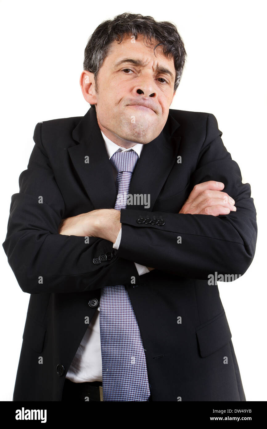 Geschäftsmann mit einem spekulativen Ausdruck stehen runzelt die Stirn an der Kamera mit seinen Armen gefaltet und Einschätzung der situation Stockfoto