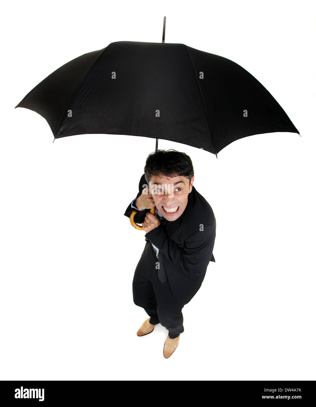 Humorvolle hohen Winkel voller Länge Porträt eines zimperlich Geschäfts unter einem Regenschirm kauernd, wie er bei schlechtem Regen schaut Stockfoto