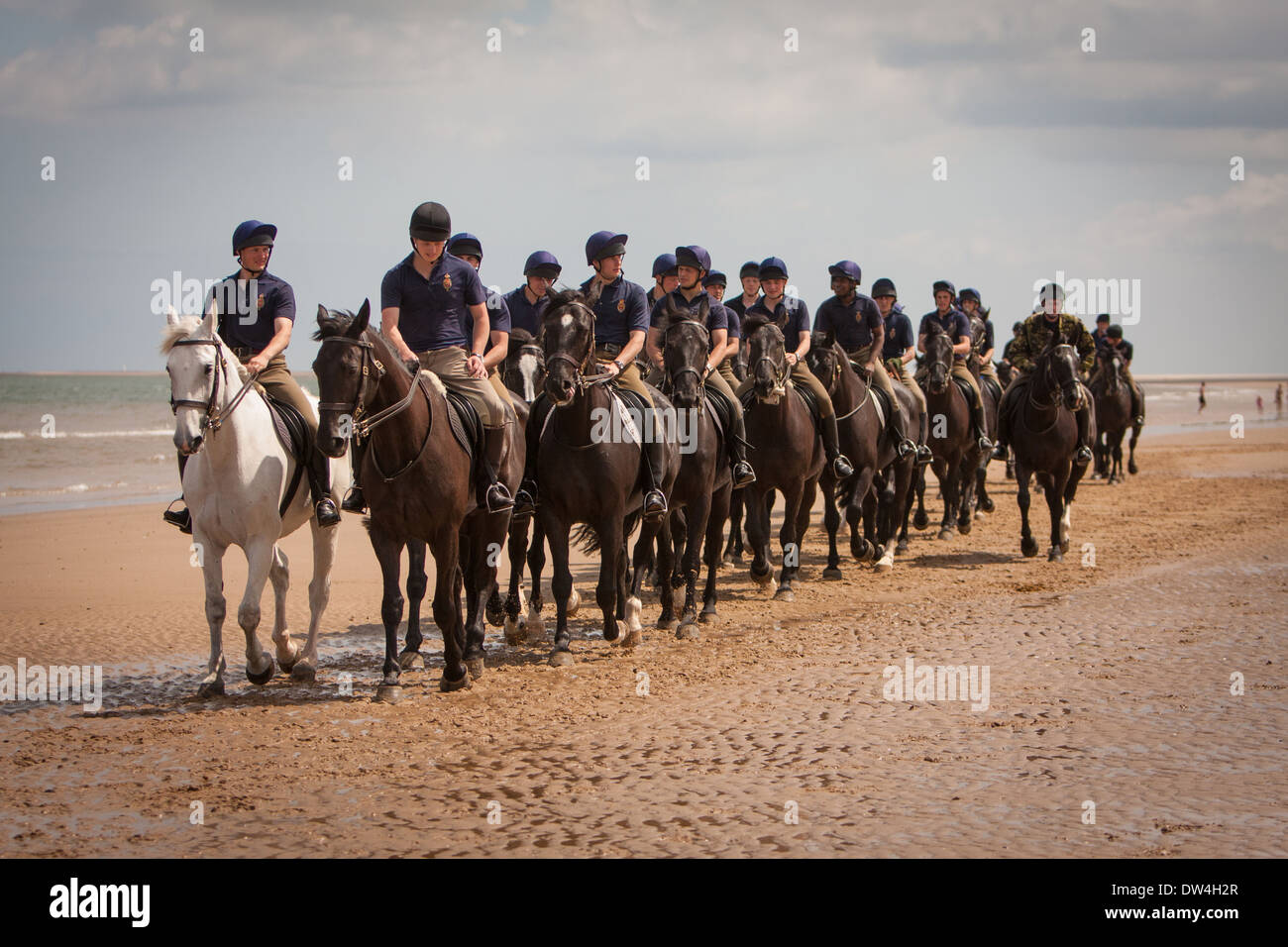 Reiter und Frauen die Blues and Royals trainieren ihre Pferde in der Brandung am Holkham Beach Norfolk, Großbritannien Stockfoto